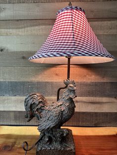 a lamp that is sitting on top of a wooden table next to a rooster figurine