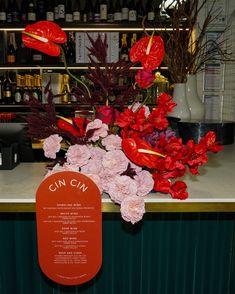 red flowers are sitting on the counter in front of wine bottles and other liquors