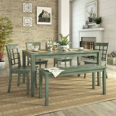 a dining room table with four chairs and a bench in front of a brick wall