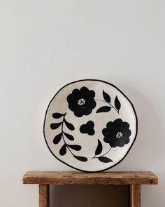 a black and white plate sitting on top of a wooden shelf next to a wall