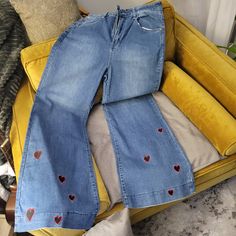 a pair of jeans with hearts on them are sitting on a yellow couch next to pillows