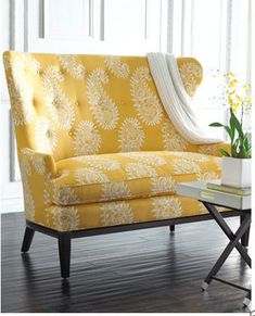 a yellow couch sitting on top of a hard wood floor next to a white table