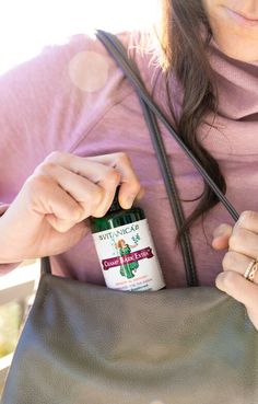 a woman holding a brown purse with a medicine bottle in her pocket and the other hand on top of it