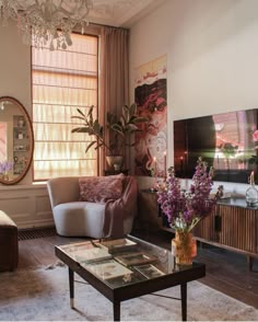 a living room filled with furniture and a chandelier hanging from the ceiling next to a window