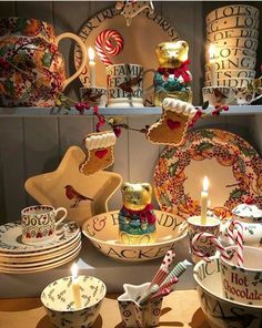 a table topped with plates and bowls filled with candy canes next to a lit candle