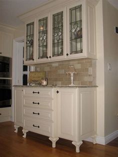 a kitchen with white cabinets and glass doors on the cupboards is pictured in this image