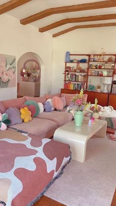 a living room filled with lots of furniture next to a wooden floor covered in pink and white pillows