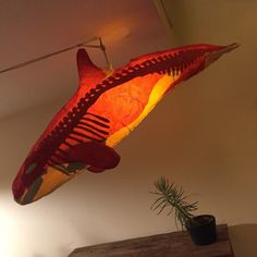 a fish lamp hanging from the ceiling in a living room next to a potted plant