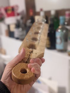 a person holding a wooden object in front of a row of wine glasses on a counter