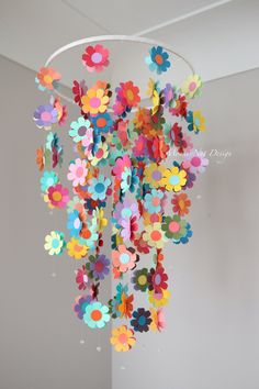 a chandelier with paper flowers hanging from it's sides in a room