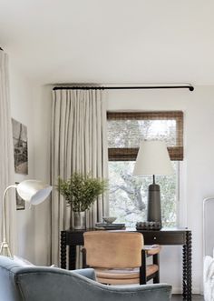 a living room filled with furniture next to a window covered in curtains and drapes