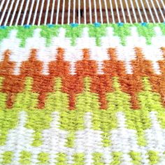 an orange, green and white knitted blanket sitting on top of a table