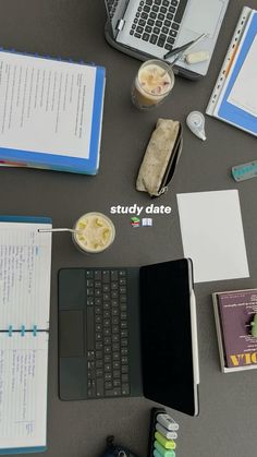 a table topped with notebooks and papers next to a laptop computer on top of a desk