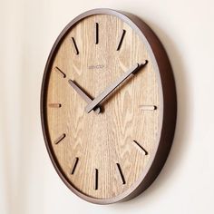 a wooden clock hanging on the wall with roman numerals and numbers in front of it