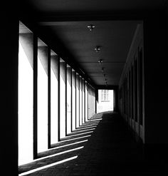 an empty hallway with rows of windows in the dark