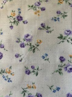 the fabric has flowers on it and is white with purple, yellow and blue colors