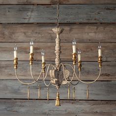 a chandelier hanging from a wooden wall with candles in the middle and one light on each side