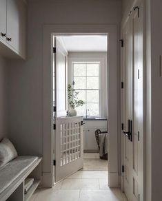 an open door leading to a bathroom with white walls and tile flooring, along with a plant on the window sill