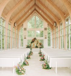 an empty church with white pews and floral arrangements