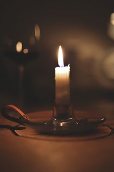 a lit candle sitting on top of a table next to a pair of pliers