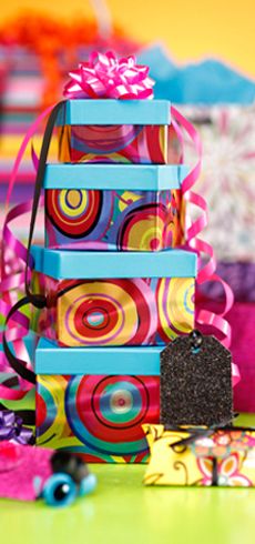 colorful boxes are stacked on top of each other with ribbons and decorations in the background