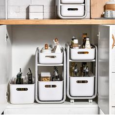 three white containers are stacked on top of each other in a kitchen cabinet with wooden shelves