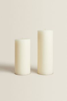 two white candles sitting next to each other