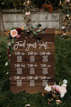 a wooden sign that says, find your seat with flowers and greenery around it