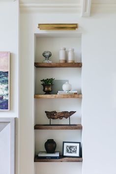 the shelves in this living room are filled with vases and other decor items on them