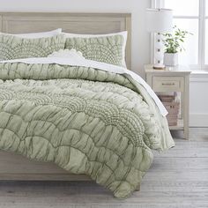 a bed with a green comforter and pillows