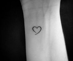 a black and white photo of a small heart tattoo on the left inner arm,