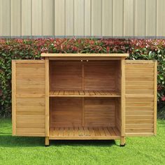 a wooden cabinet sitting on top of a green grass covered field next to a bush