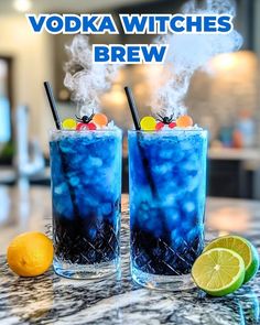 two glasses filled with blue liquid sitting on top of a counter next to an orange slice