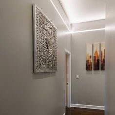 an empty hallway with two paintings on the wall and wood flooring in front of it