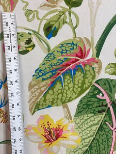 a large ruler is next to a flower print fabric with leaves and flowers on it