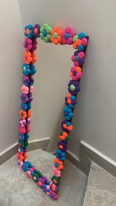 an odd shaped object made out of colored balls on the floor next to a wall