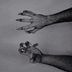 two hands reaching for each other with their fingers extended up to the ground, in black and white