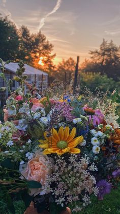 a vase filled with lots of different types of flowers on top of a grass field