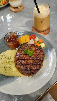 a plate with steak, mashed potatoes and vegetables on it next to a drink