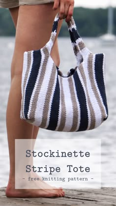 a woman is holding a striped bag on the dock with her feet in the water