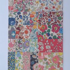 a colorful patchwork quilt with flowers and leaves on the front, hanging on a wall