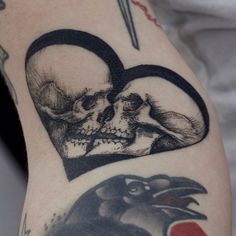 a couple of skulls sitting next to each other on a person's arm with scissors