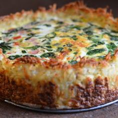 a close up of a pie on a pan with cheese and spinach toppings