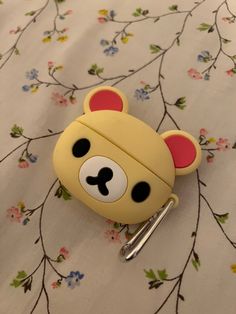 a yellow and black bear shaped key chain on a flowered tablecloth with flowers