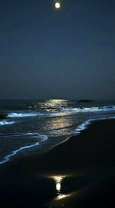 the moon shines brightly in the night sky over an ocean with waves and sand