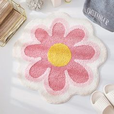 a bath mat with a pink flower on it next to slippers and other accessories