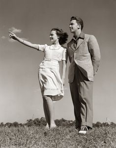 a man and woman standing on top of a grass covered field next to each other