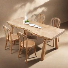 a wooden table with four chairs around it and a vase on the table next to it