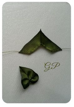 two pieces of cloth with green bows tied to them on a white tablecloth that says g p