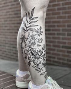 a woman's leg with flowers and leaves tattooed on the side of her leg